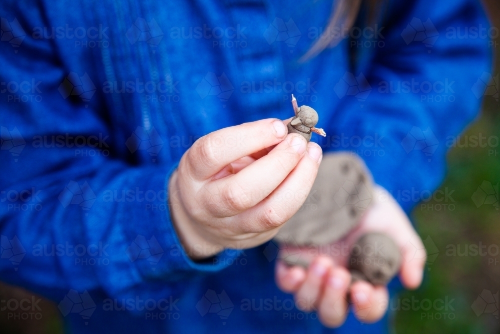 Little girl holding snowman made of clay - Australian Stock Image