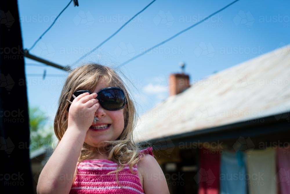 Little girl in backyard wearing sunglasses - Australian Stock Image