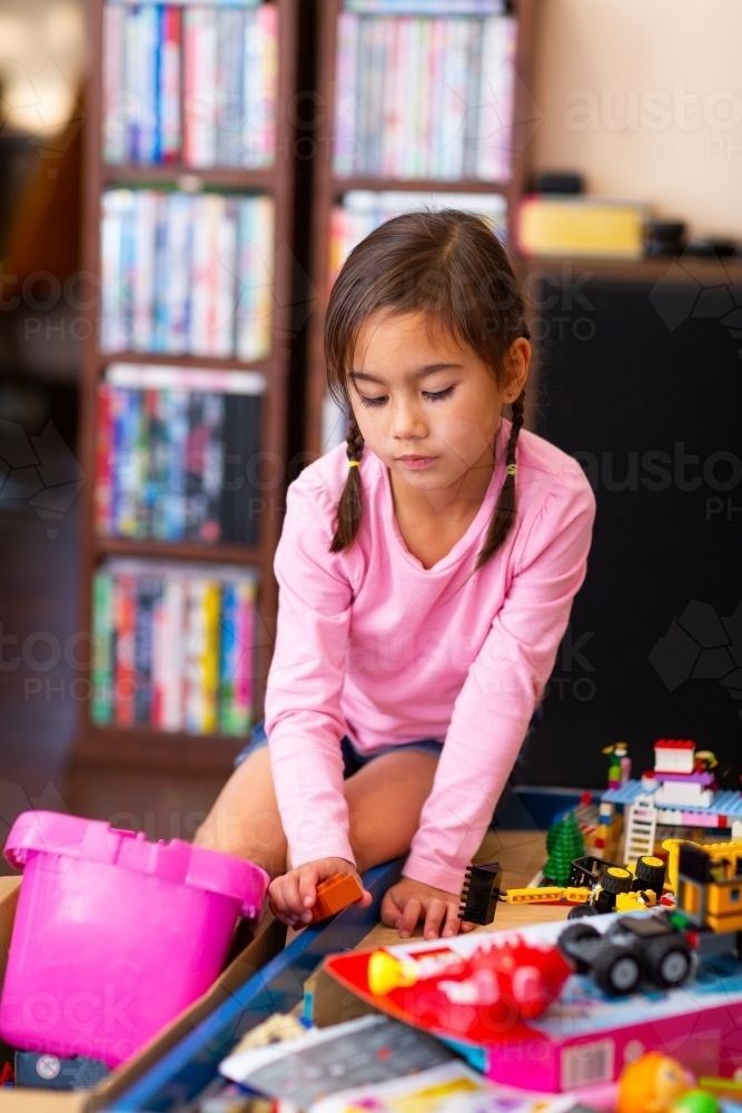 Little girl in pink playing with toys at home - Australian Stock Image