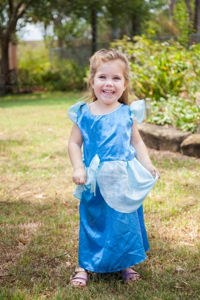 Little girl in princess dress ups costume smiling at camera - Australian Stock Image