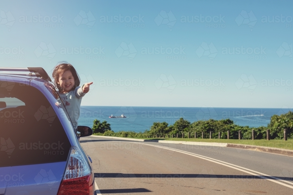 Little girl in the car on roadside with ocean background - Australian Stock Image