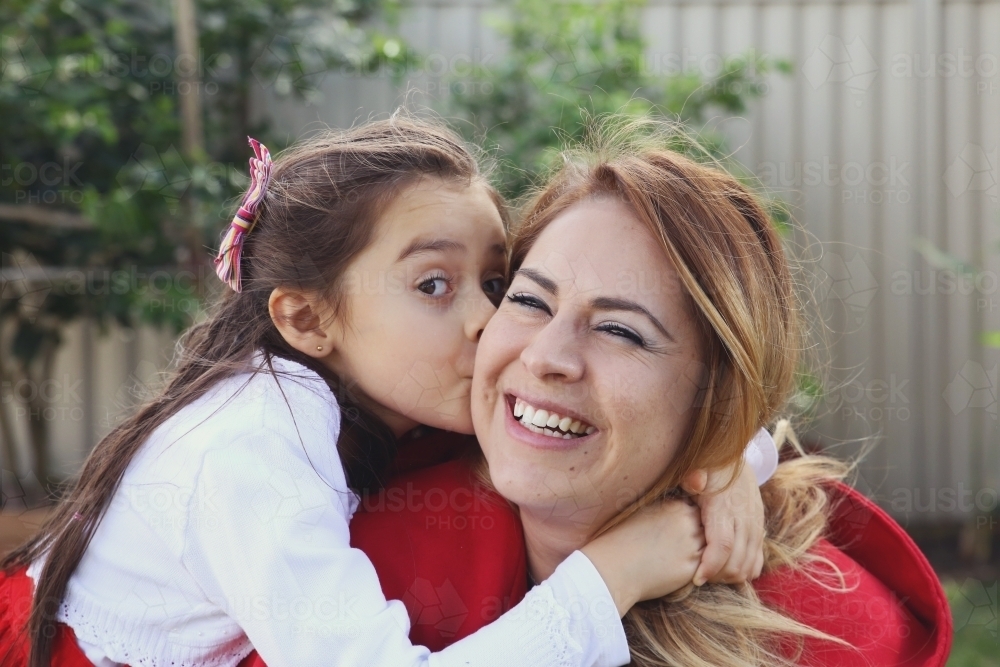 Little girl kissing her mother - Australian Stock Image