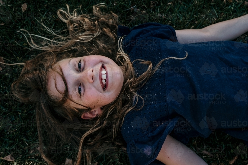 Little girl lies down on the grass - Australian Stock Image