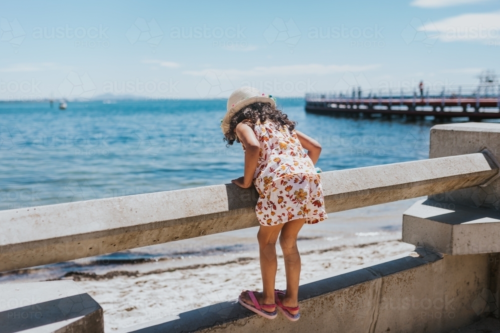 Little girl looking at the sea over railing - Australian Stock Image