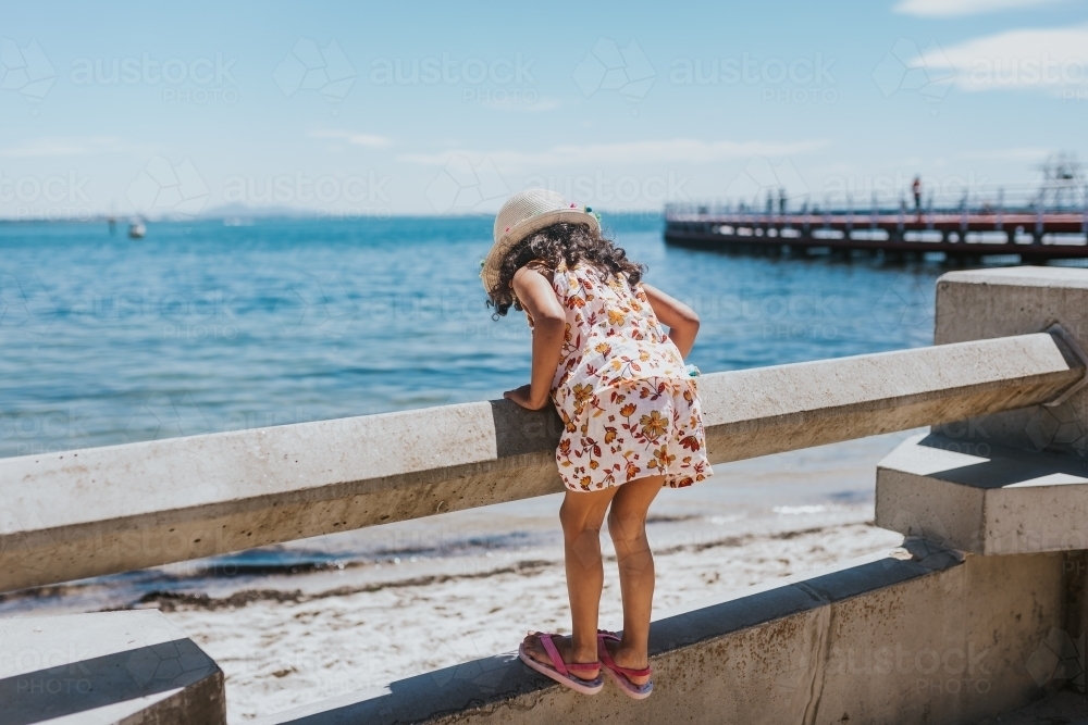 Little girl looking at the sea over railing - Australian Stock Image