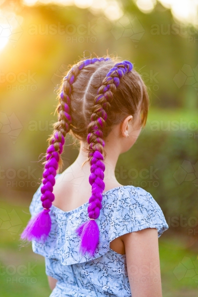 Little girl looking away fun purple braids in hair - Australian Stock Image