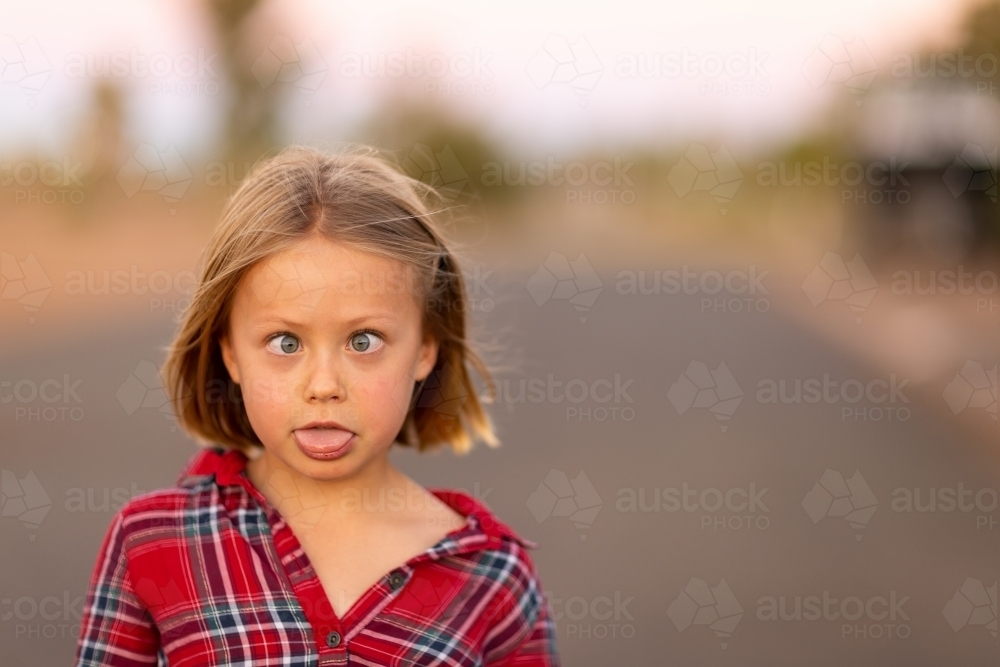 little girl making funny face with cross eyes and tongue out - Australian Stock Image