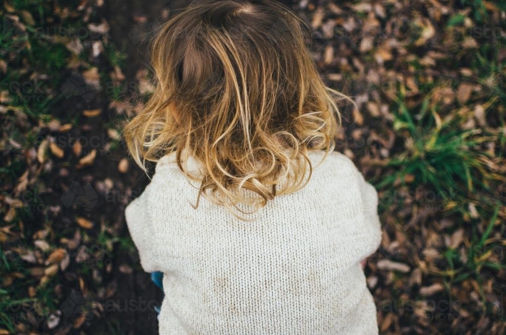 Little girl outside in garden with blonde curls - Australian Stock Image