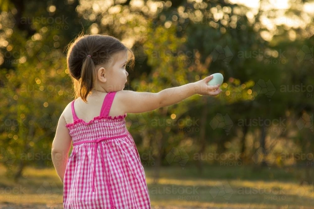 Little girl outside offering to share her Easter eggs - Australian Stock Image