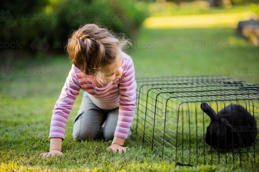 Little girl outside pretending to be a rabbit with her bunny - Australian Stock Image