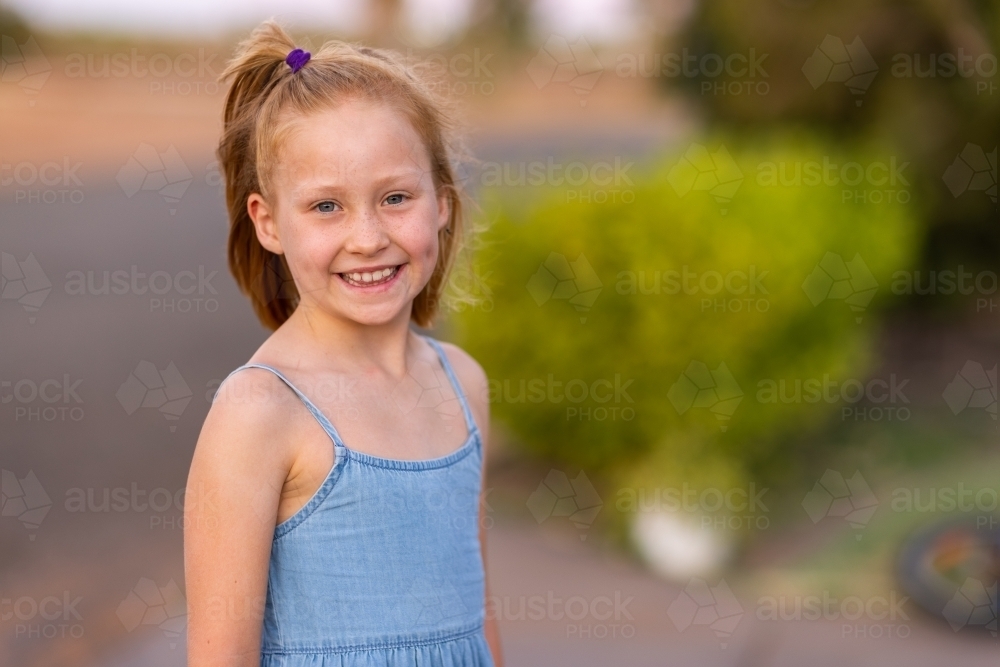 little girl outside smiling showing teeth and dimples - Australian Stock Image