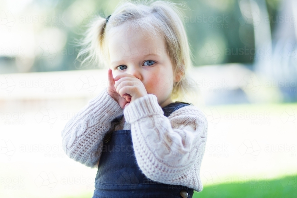 Little girl outside sucking her thumb - Australian Stock Image