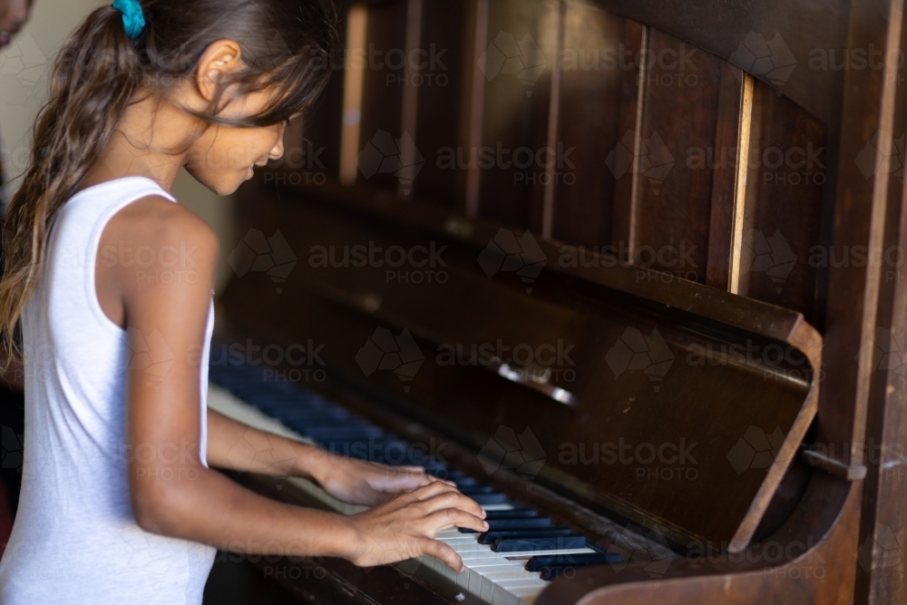 little girl playing at playing piano - Australian Stock Image