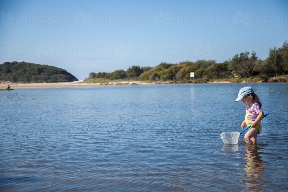 Little girl playing in the water where the river meets the sea - Australian Stock Image