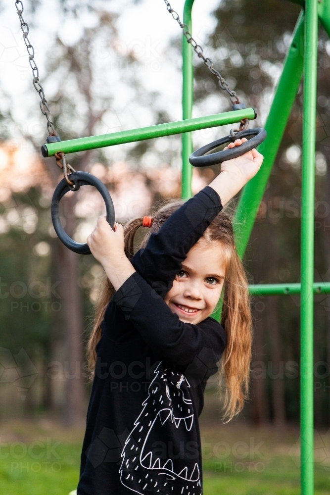 Image of little girl playing on swingset rings Austockphoto