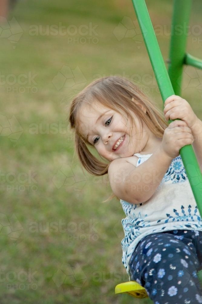 Little girl playing on the swings in the backyard - Australian Stock Image