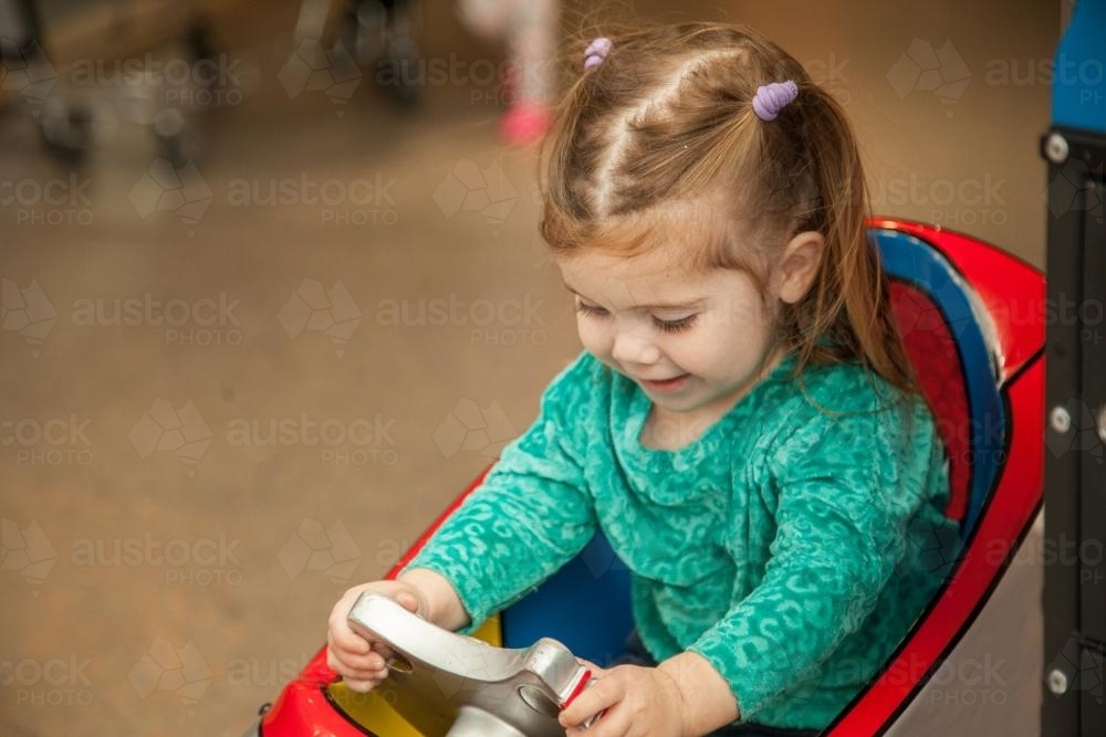 Little girl playing on two dollar kiddie ride at the supermarket - Australian Stock Image