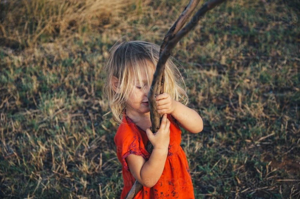 Little girl playing with a stick - Australian Stock Image