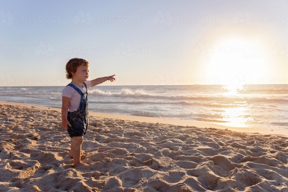 Little Girl Pointing Out To The Ocean At Sunset - Australian Stock Image