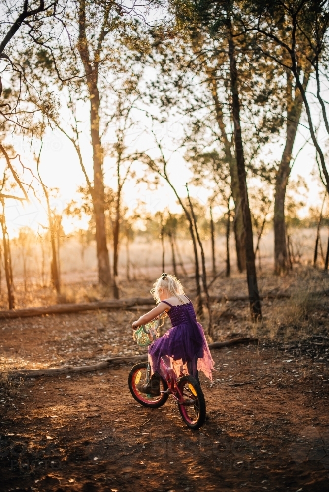 Little girl riding her bike at last light on farmland - Australian Stock Image