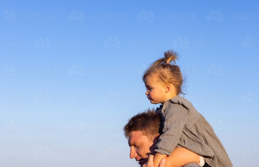 little girl riding high on daddy's shoulders - Australian Stock Image