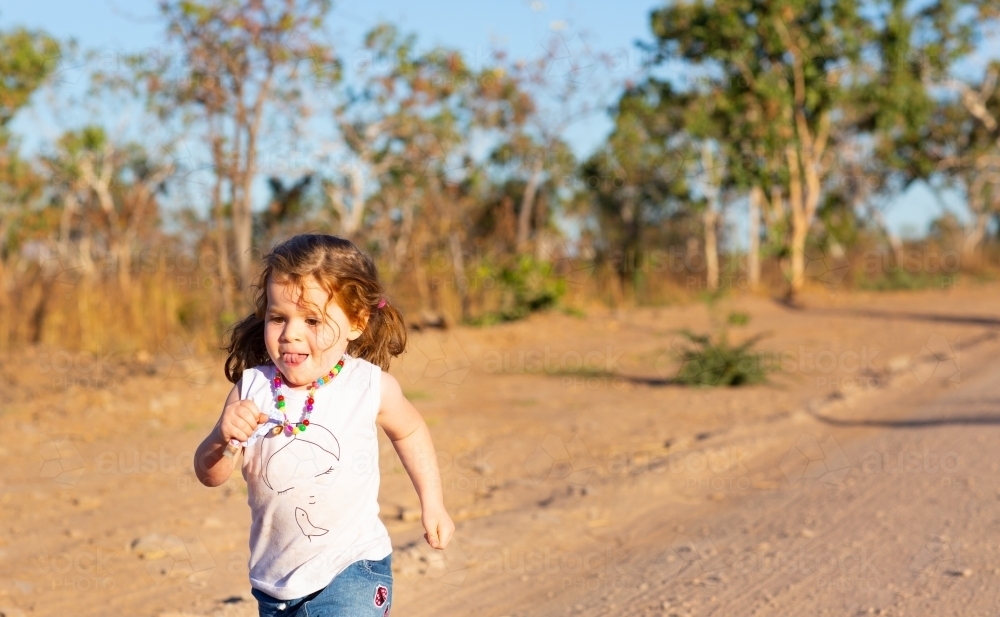 Little girl running along a dirt road - Australian Stock Image