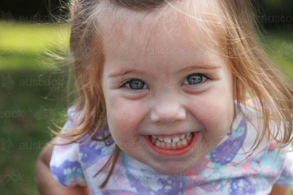 Little girl's grinning face - Australian Stock Image