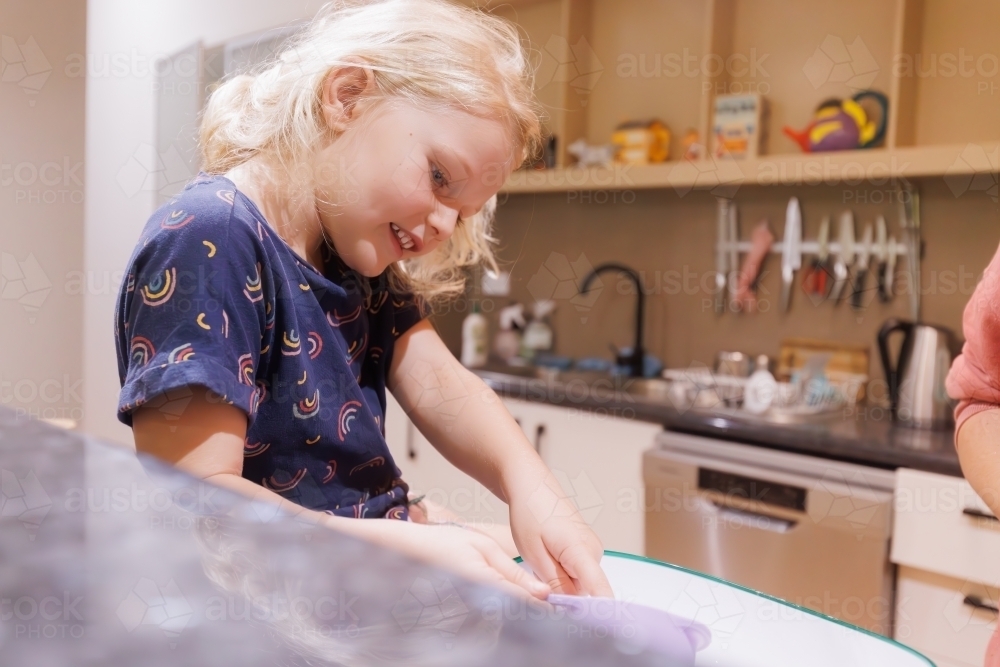 Image of Little girl sitting on kitchen bench measuring ingredients ...