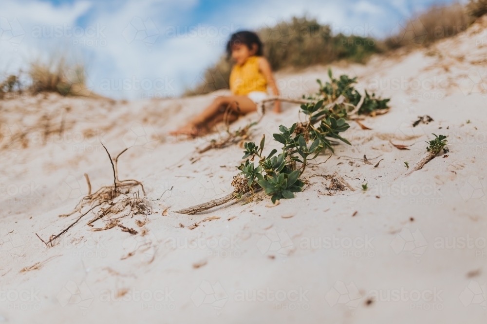 Little girl sliding down sand dunes - Australian Stock Image