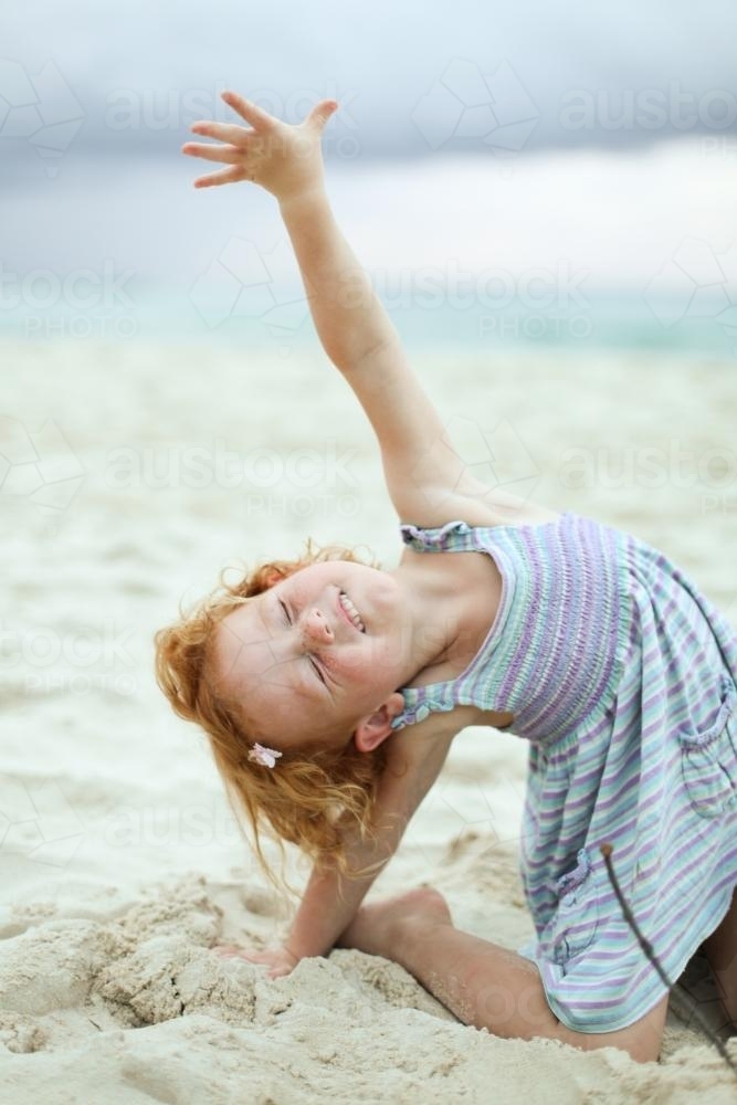 Little girl stretching at the beach - Australian Stock Image