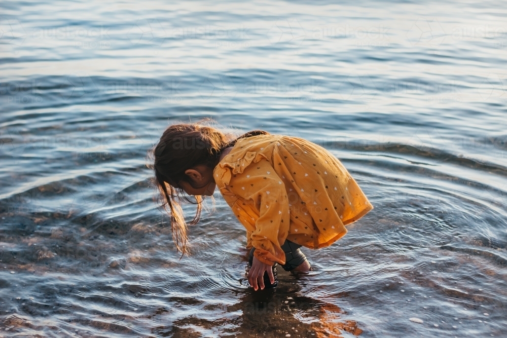 Little girl touching water in the sea - Australian Stock Image