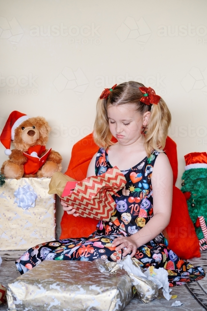 Little girl unhappy with a Christmas gift she has opened - Australian Stock Image