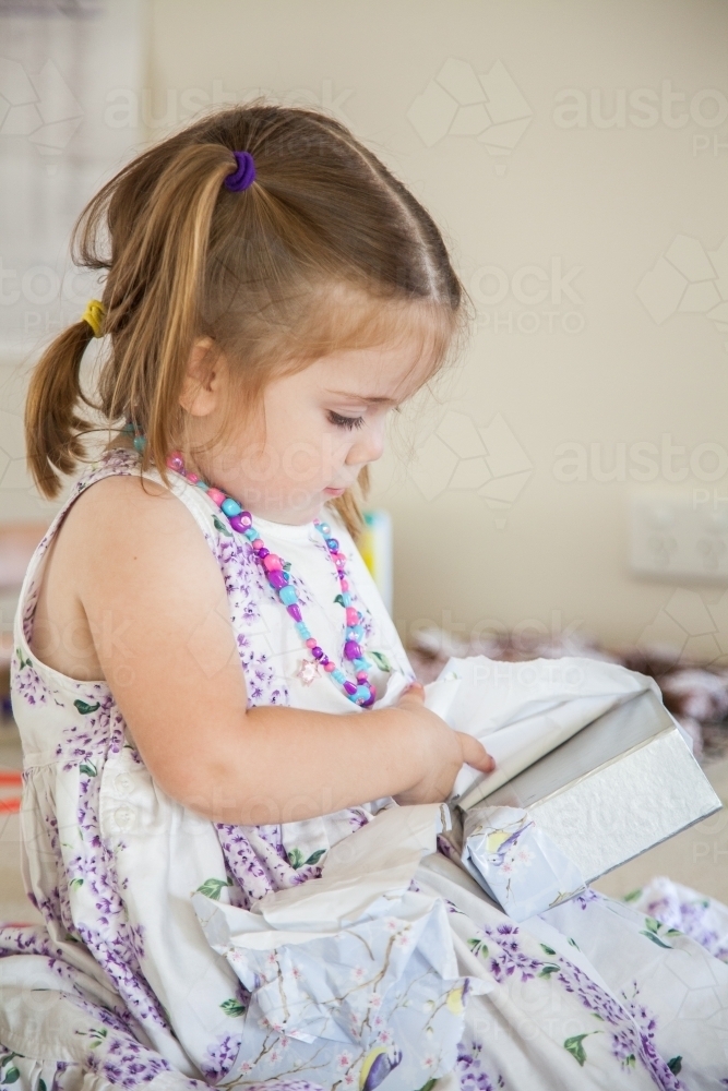 Little girl unwrapping gifts on her birthday - Australian Stock Image