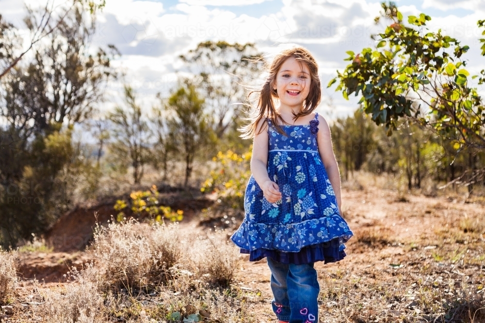 Little girl walking through paddock - Australian Stock Image