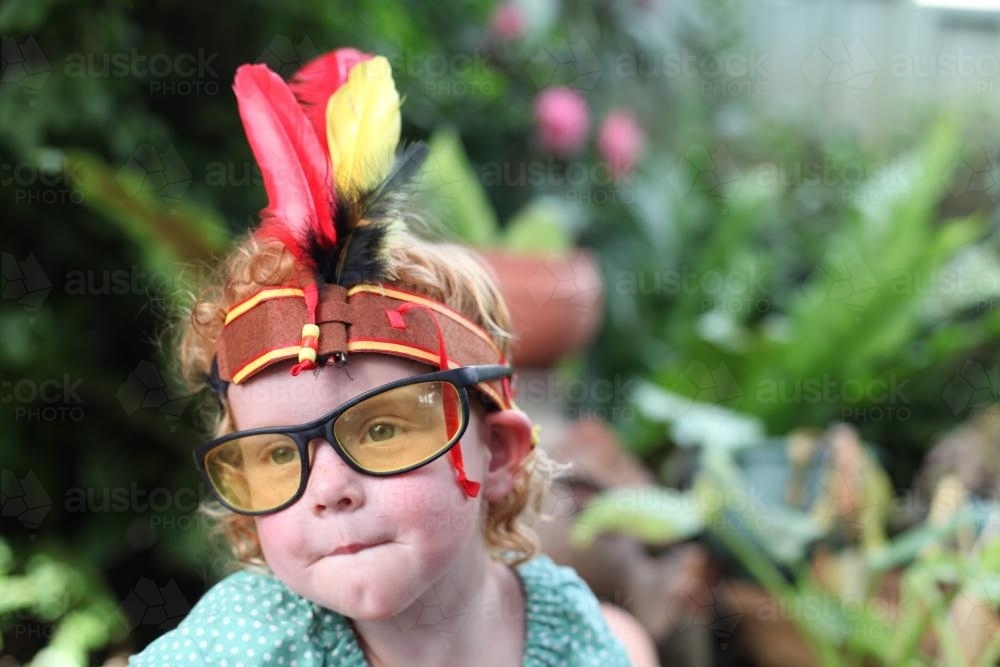 Little girl wearing dress up Indian headband and glasses - Australian Stock Image