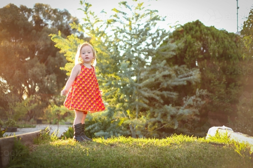 Image of Little girl wearing red dress exploring lush green garden ...