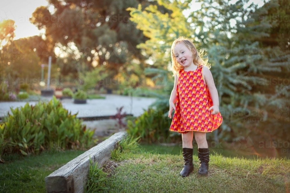 Image of Little girl wearing red dress exploring lush green garden ...