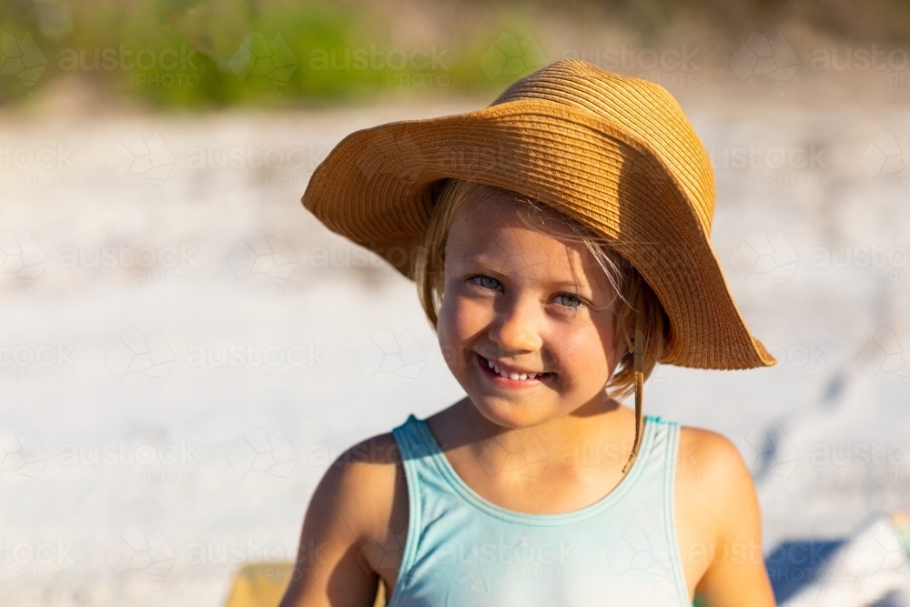 little girl wearing straw hat and smiling at the camera - Australian Stock Image