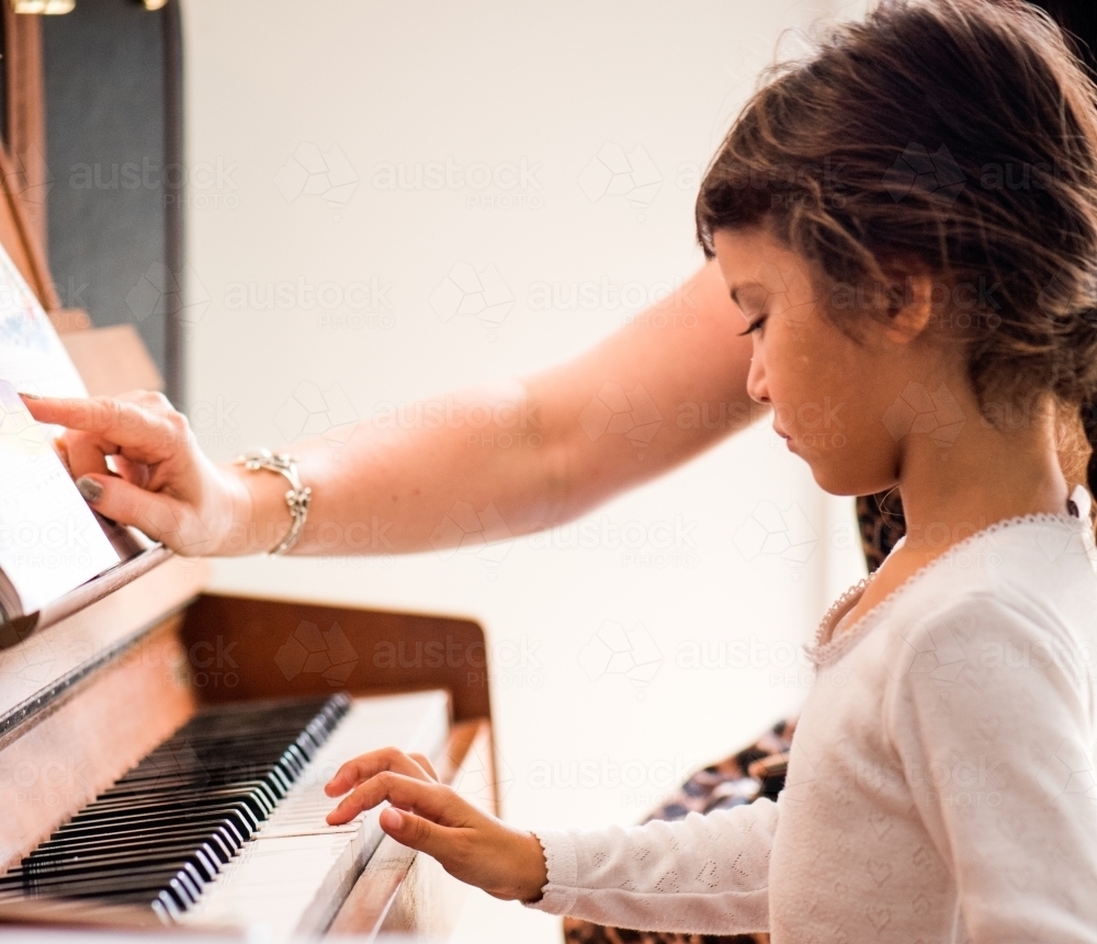 Little girl with Asian ethnicity learning to play the piano. - Australian Stock Image