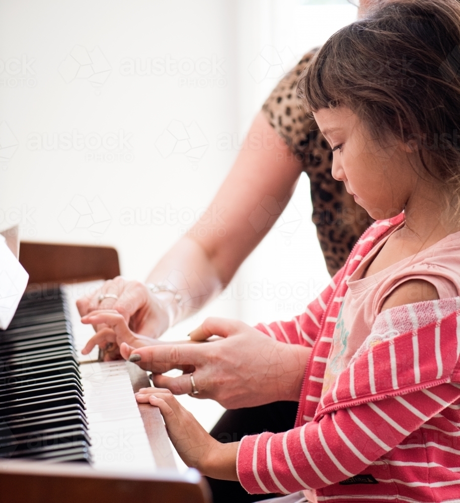 Little girl with Asian ethnicity learning to play the piano. - Australian Stock Image