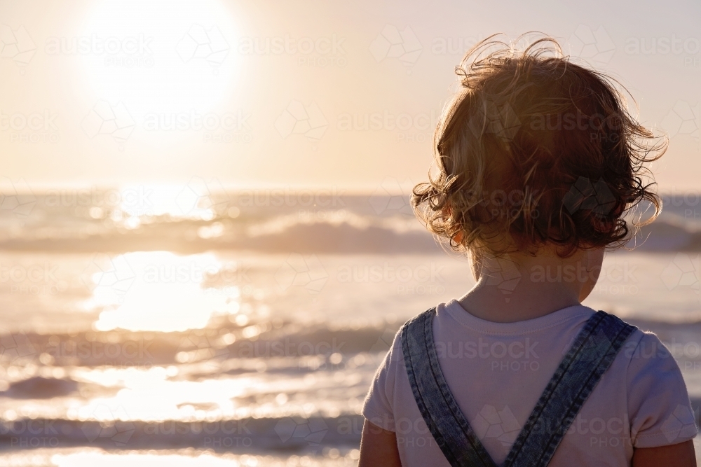 Little Girl With Curly Hair Looking Out To The Ocean At Sunset - Australian Stock Image