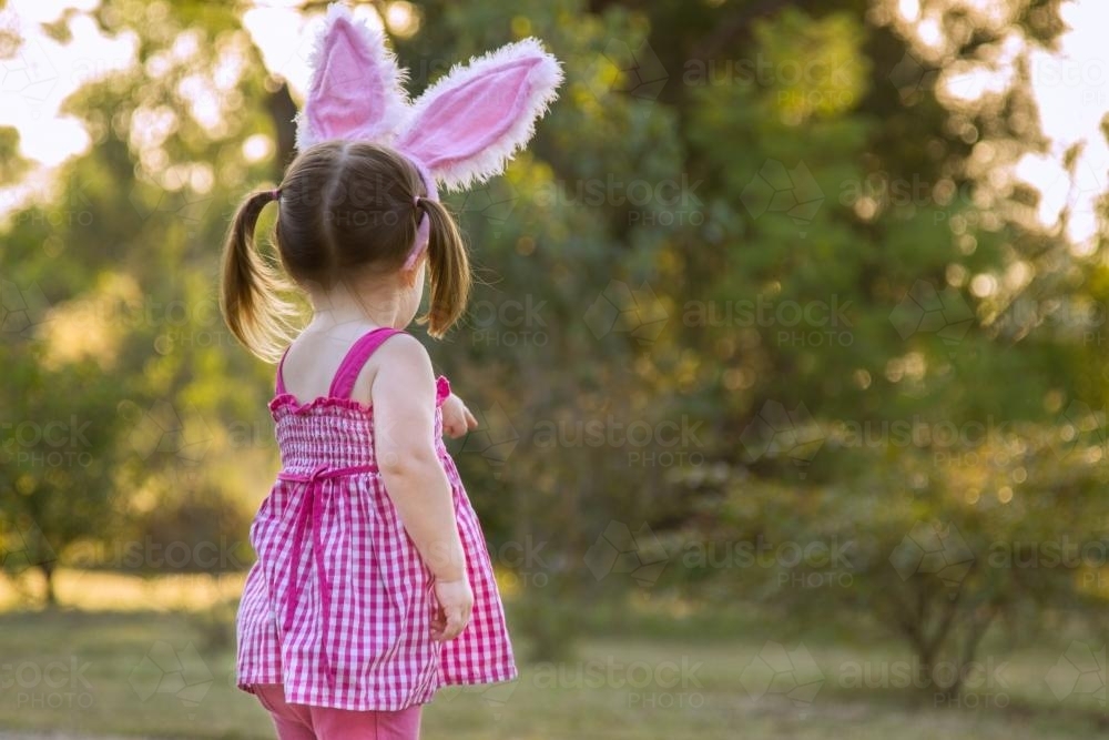Little girl with Easter bunny ears pointing away - Australian Stock Image