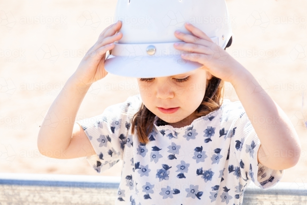 Little girl with hands on safety horse riding helmet she is wearing - Australian Stock Image