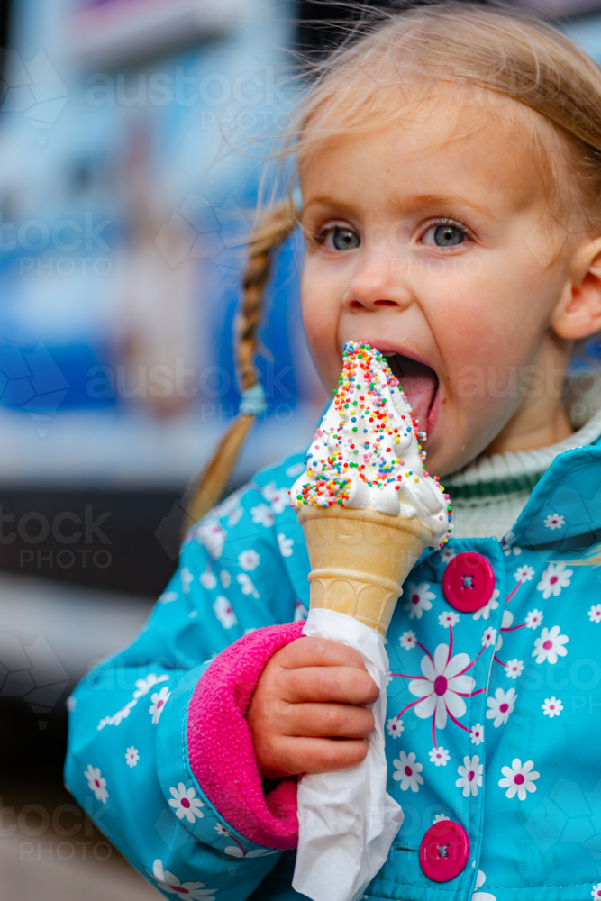 Little girl with ice cream covered in hundreds and thousands from ice-cream van - Australian Stock Image