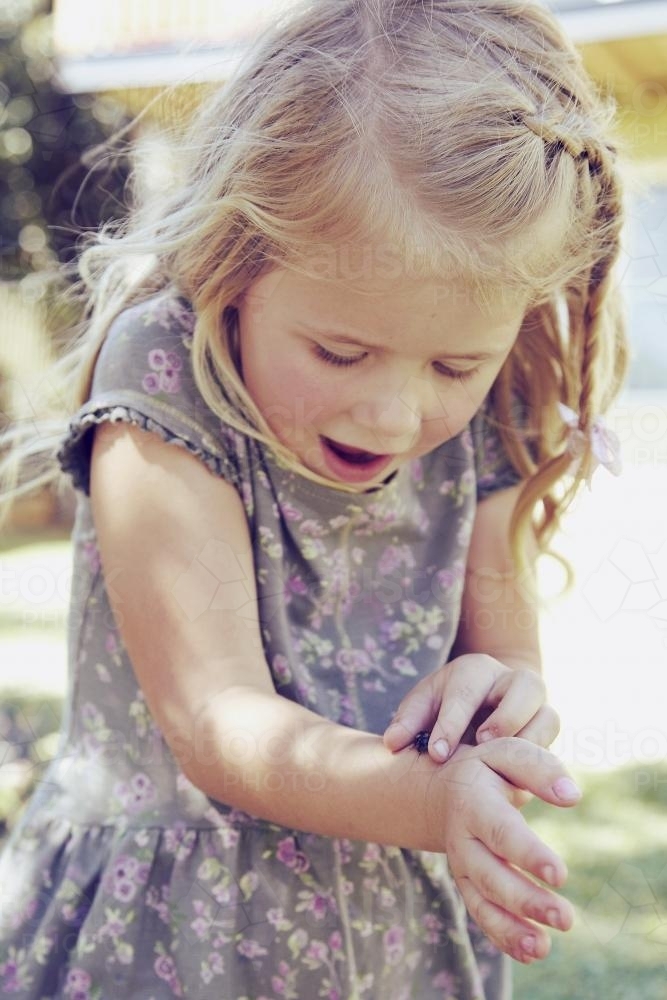 Little girl with ladybug on her arm - Australian Stock Image