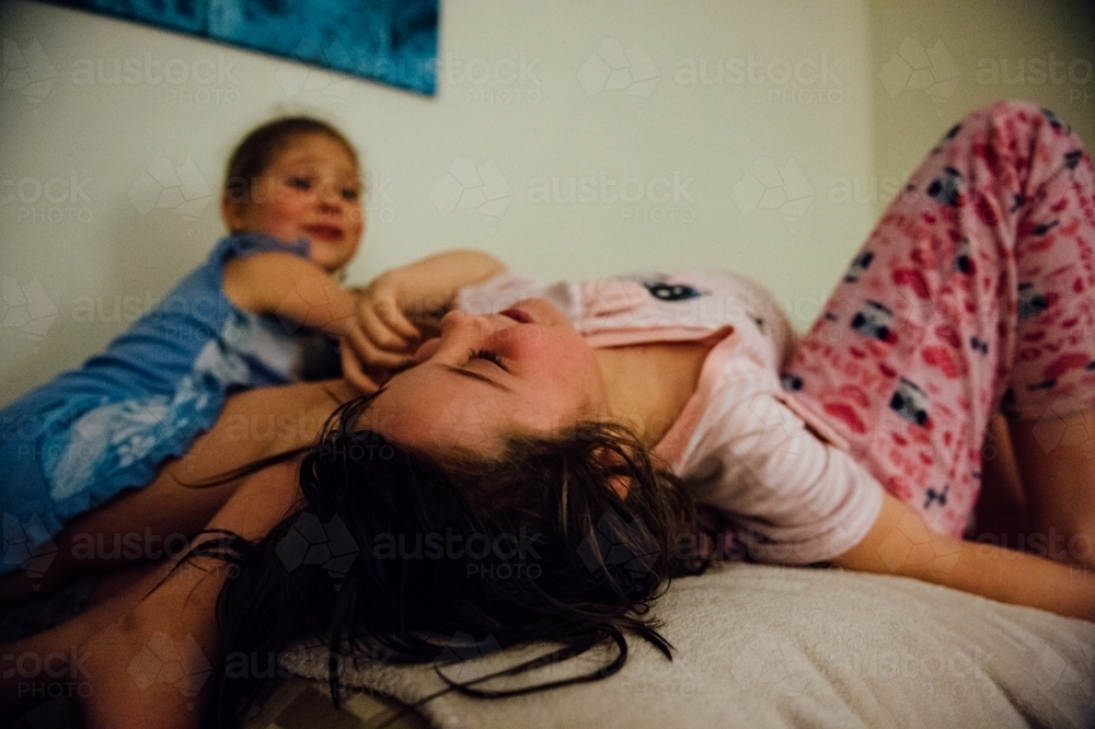 Little girls playing on a bed - Australian Stock Image