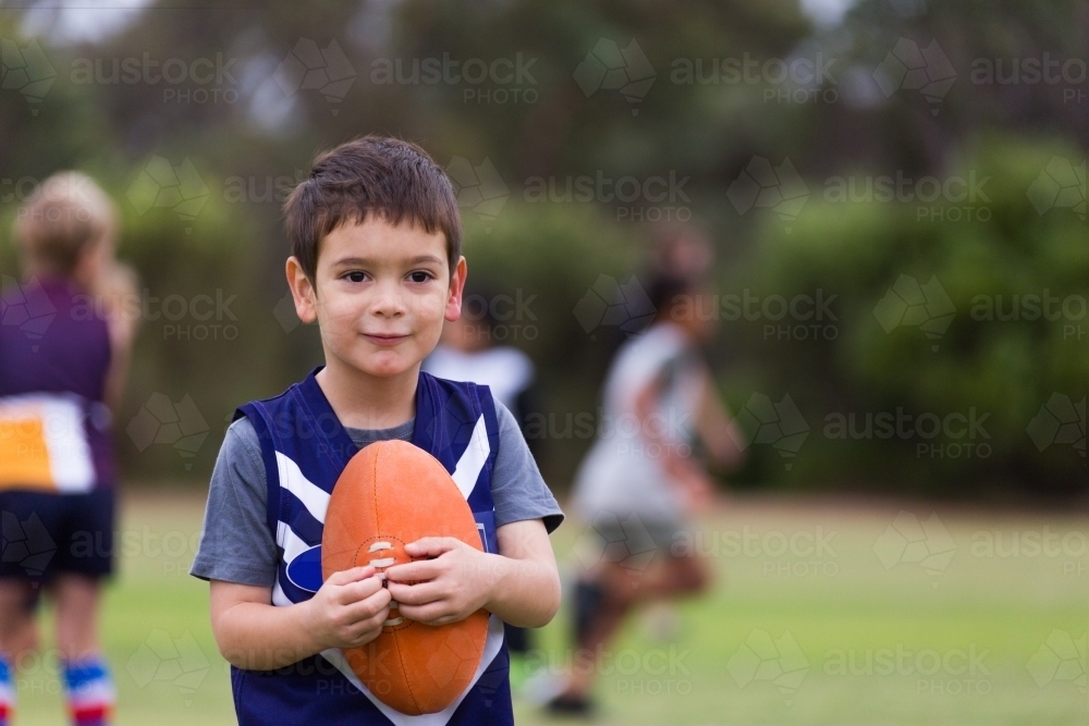 Little kid at auskick with football - Australian Stock Image