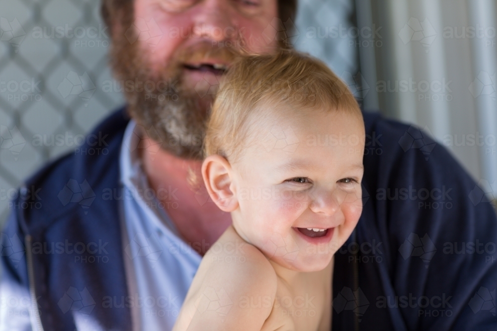 Little kid laughing with man in background - Australian Stock Image