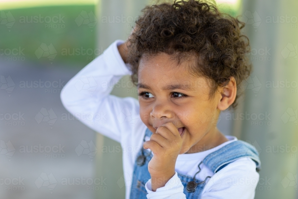 Little kid looking off to side in white and denim - Australian Stock Image
