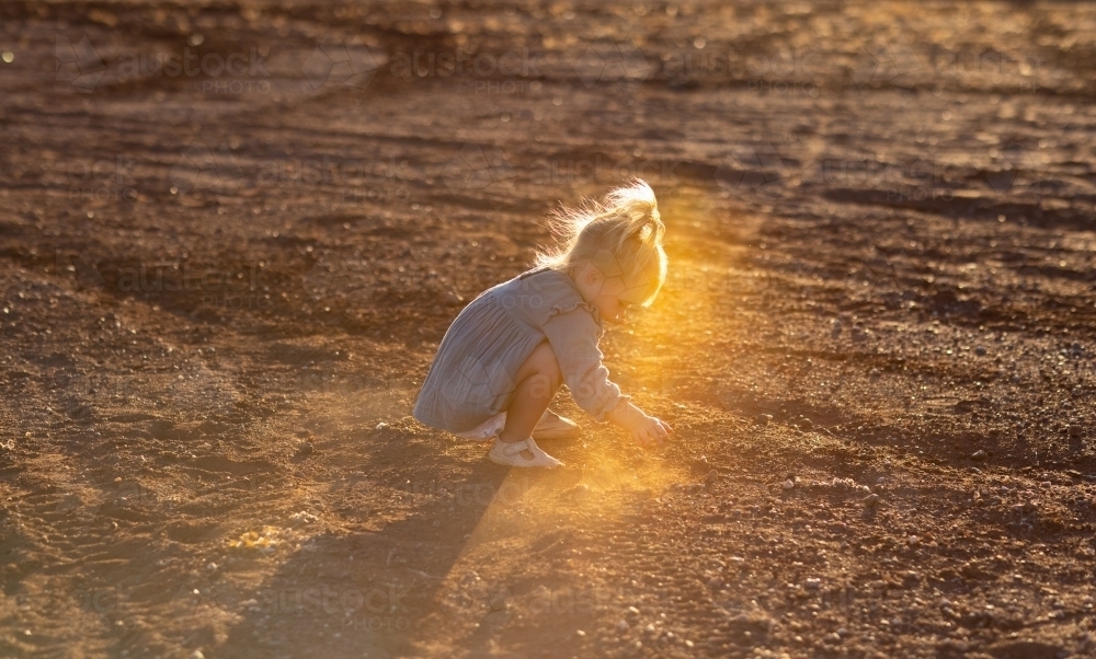 little kid playing in the dirt with backlight - Australian Stock Image